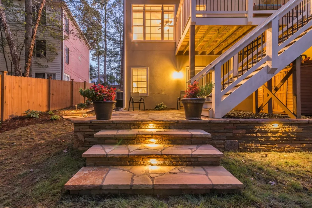 Cozy backyard with stone steps, outdoor lighting, and potted plants